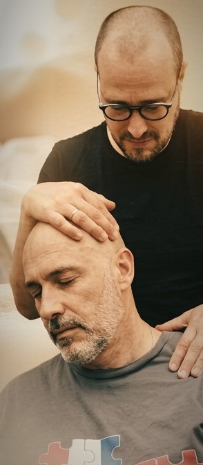 Un praticien pose une main sur le front d’une personne et l’autre sur son épaule pendant un soin